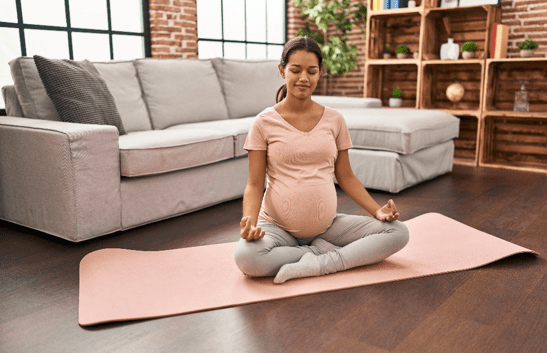 Pregnant woman practicing prenatal yoga at home, promoting healthy lifestyle and relaxation during IVF treatment