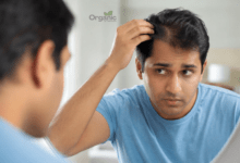 आईने में अपनी हेयरलाइन चेक करता व्यक्ति, जेनेटिक hair fall के संकेतों को दर्शाता हुआ