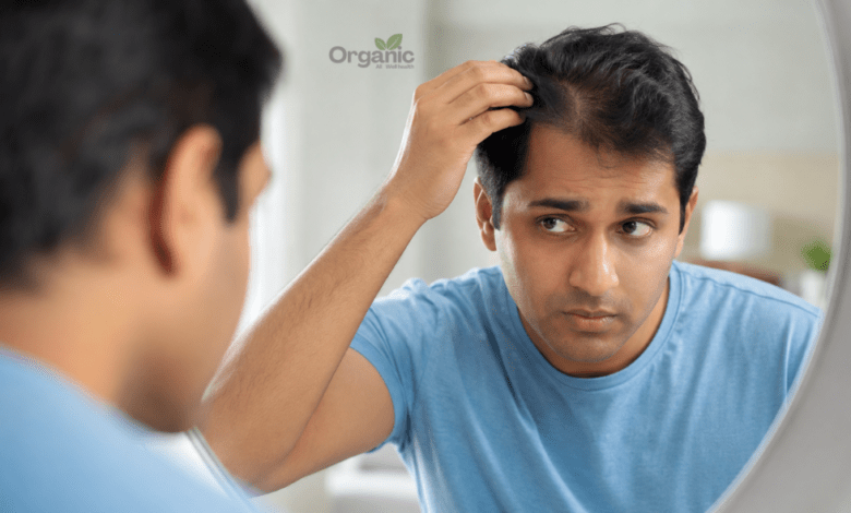आईने में अपनी हेयरलाइन चेक करता व्यक्ति, जेनेटिक hair fall के संकेतों को दर्शाता हुआ